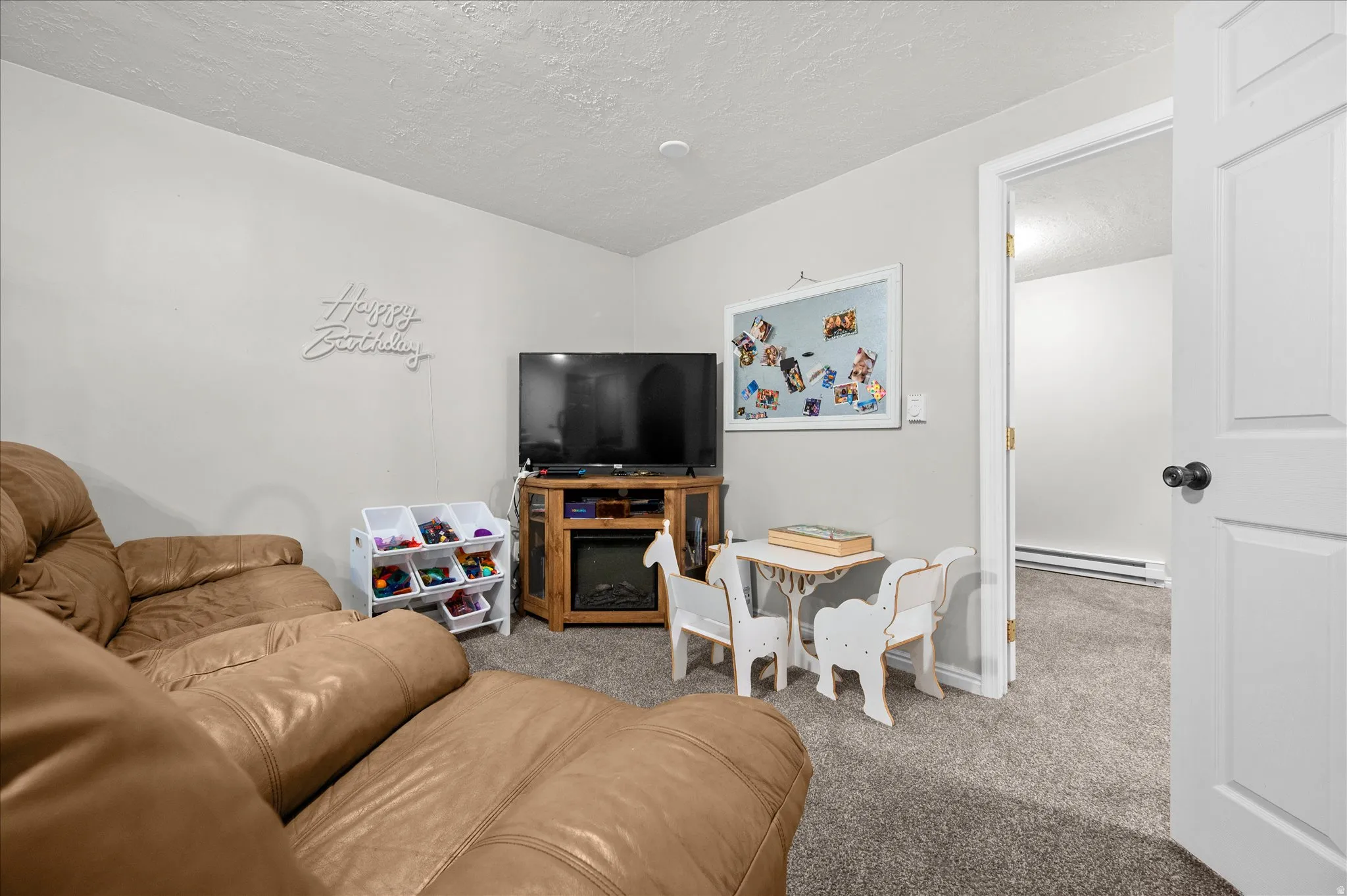 Living room featuring carpet, a baseboard heating unit, and a textured ceiling