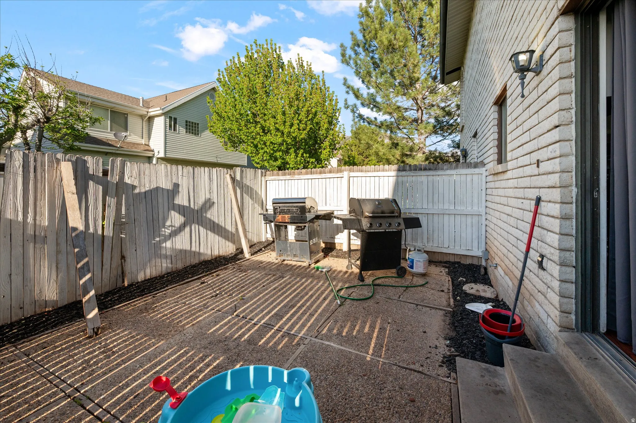Fenced backyard with grilling area and a patio