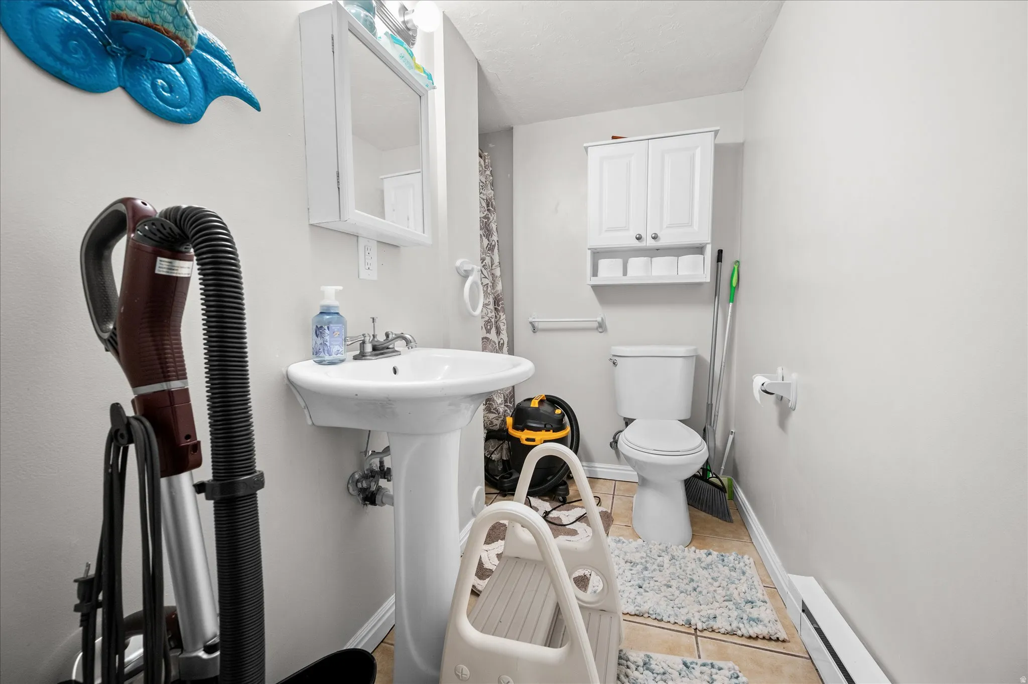 Bathroom with a baseboard heating unit and light tile patterned floors