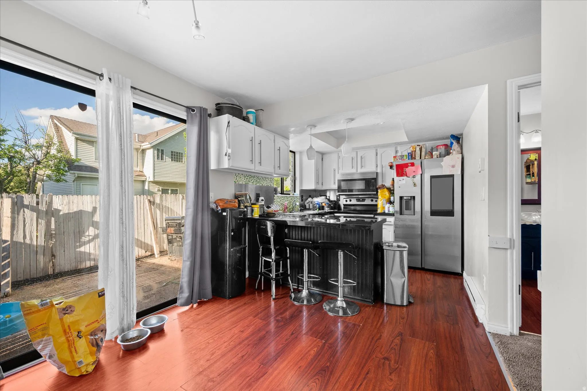 Kitchen with a peninsula, stainless steel appliances, dark wood-type flooring, dark countertops, and a kitchen bar