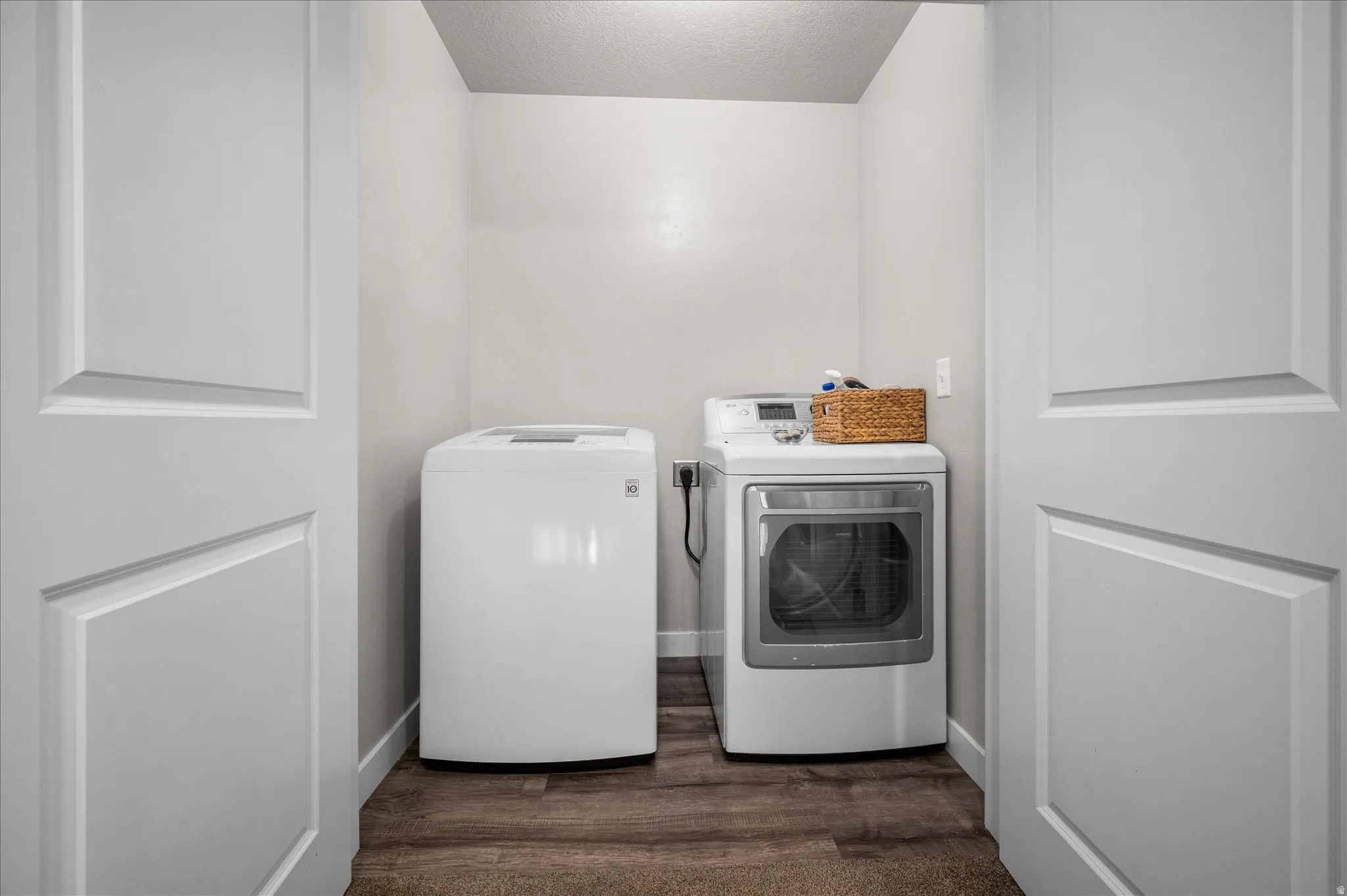 Laundry area with a textured ceiling, dark wood-type flooring, and washer and clothes dryer