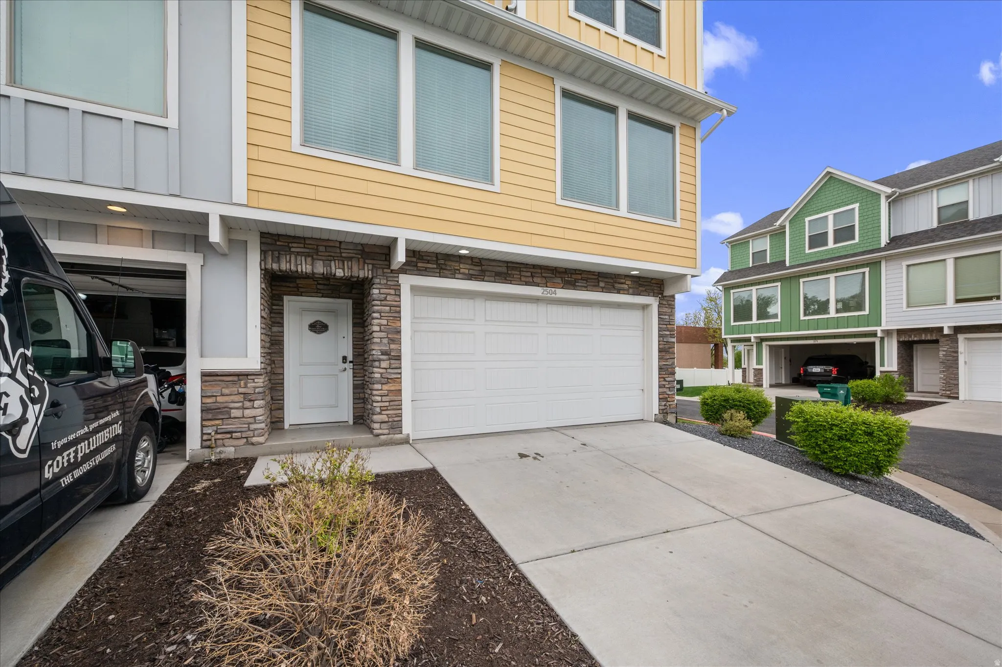 View of front of home featuring stone siding, an attached garage, driveway, and board and batten siding