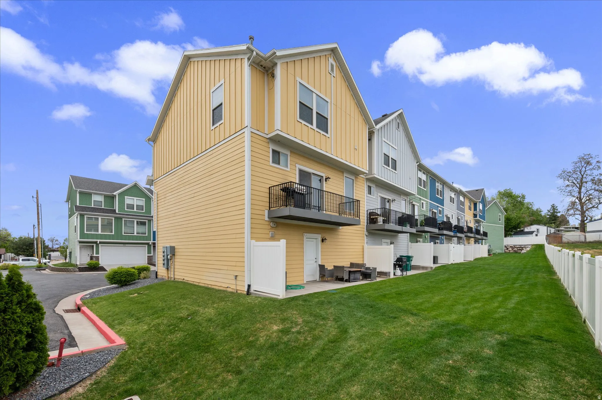 Back of property featuring board and batten siding, a patio, a residential view, and a balcony