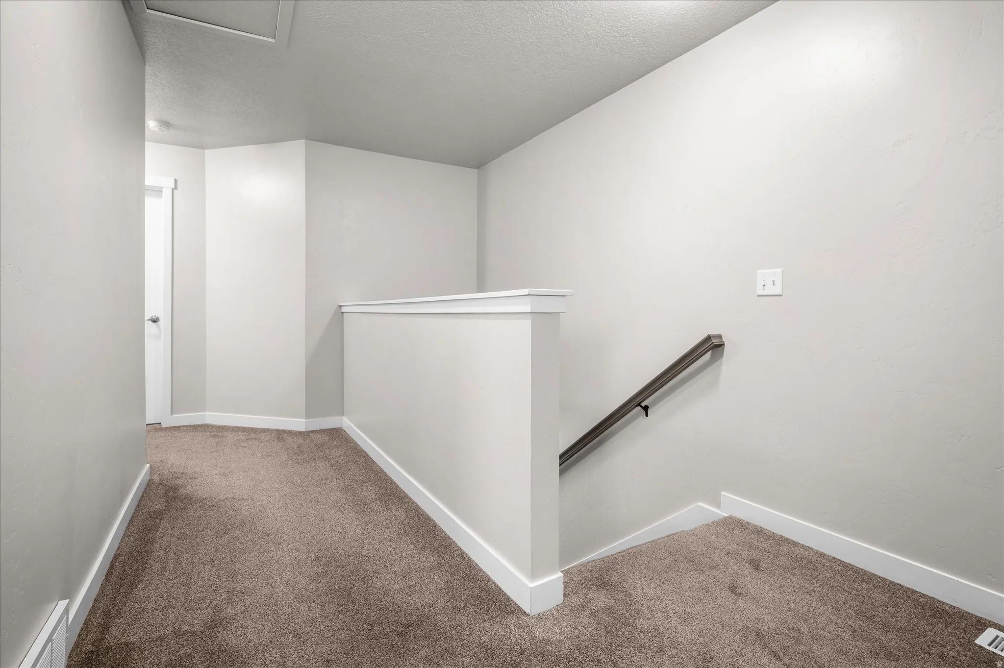 Corridor with an upstairs landing, carpet floors, and a textured ceiling