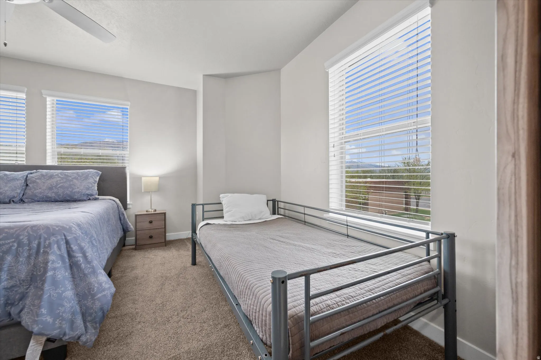 Carpeted bedroom with a ceiling fan and baseboards
