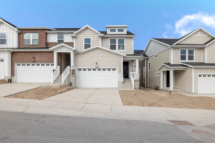 Two-story exterior with a mix of siding and brick, featuring an attached garage and concrete driveway