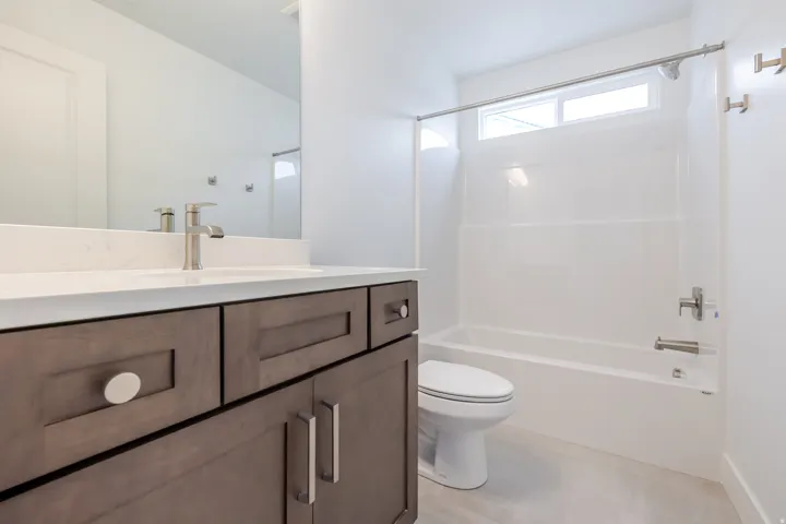 Vanity with light wood-finish cabinetry, white countertop, and brushed nickel hardware