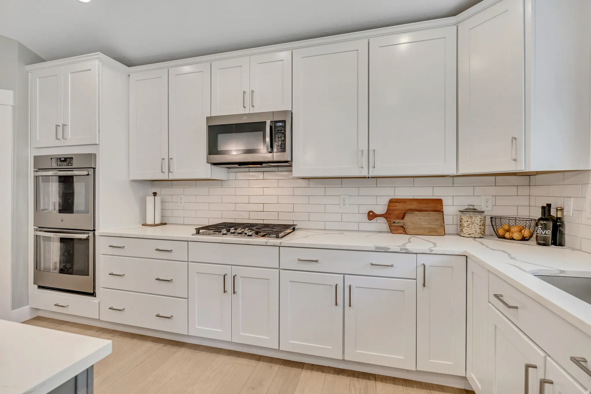Kitchen featuring white cabinetry, stainless steel appliances, light wood-style floors, and recessed lighting