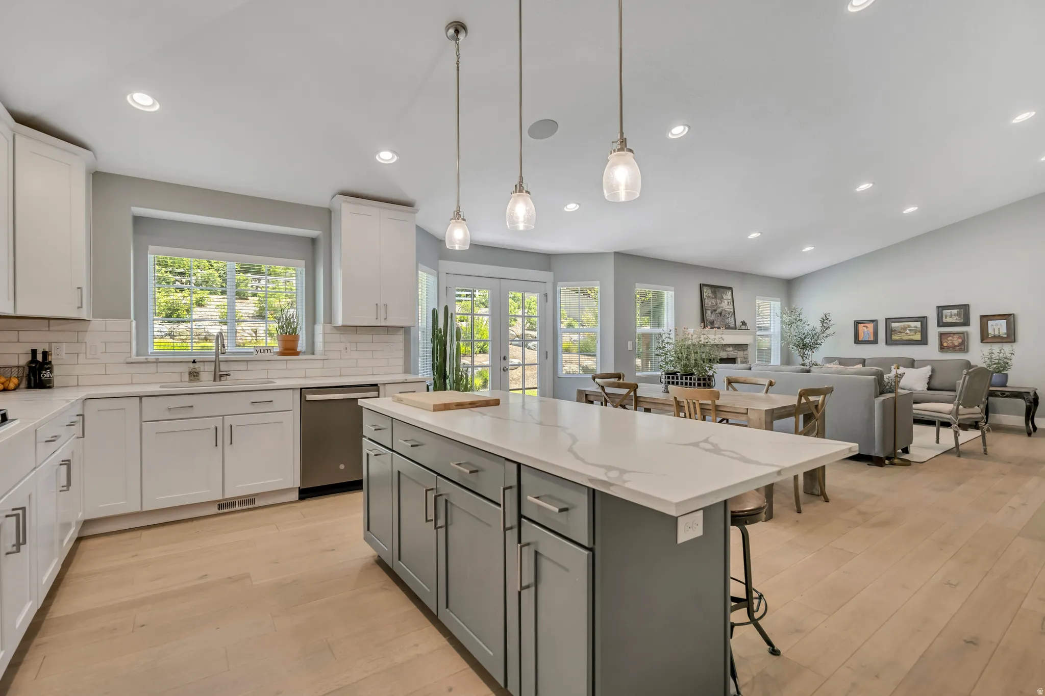 Dual tone kitchen with dual tone cabinetry, decorative backsplash, light wood finished floors, light stone counters, and lofted ceiling