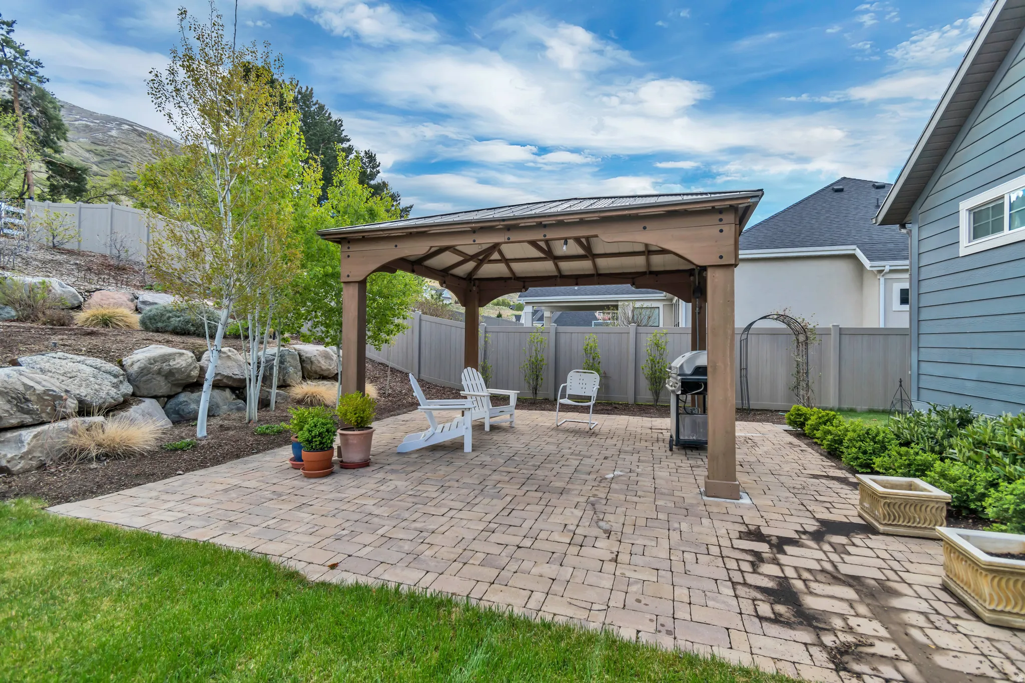 Fenced backyard featuring a gazebo, a patio area, and a grill