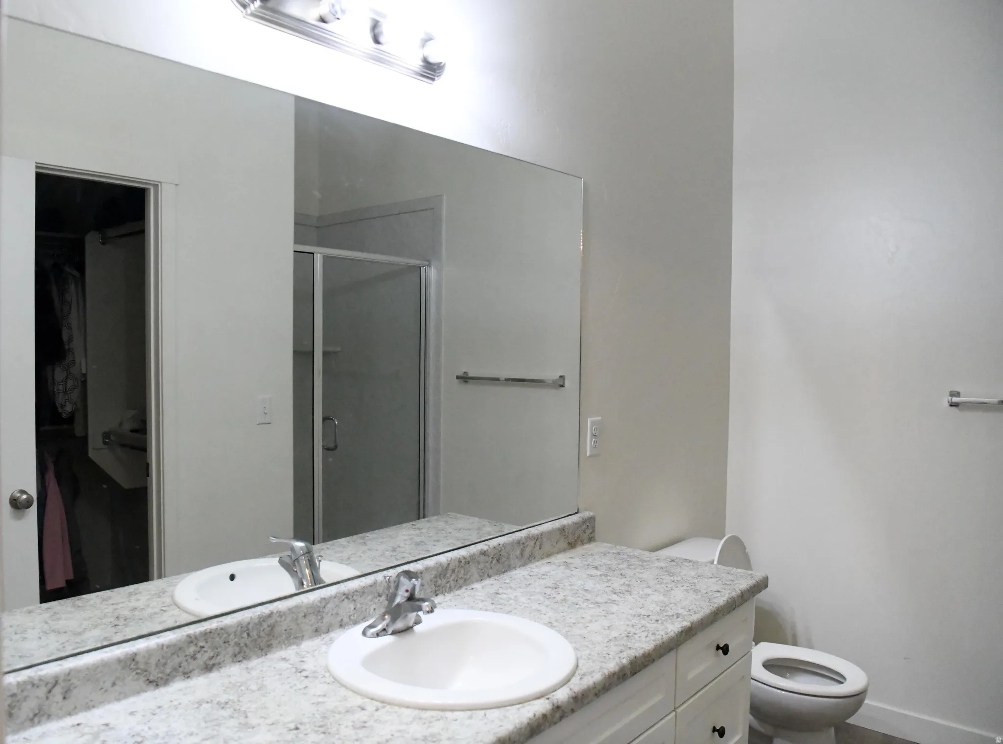 Primary bath shower stall, vanity, and a walk in closet
