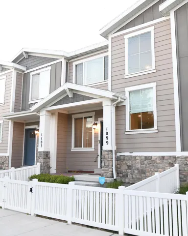 View of front of property with covered porch, stone siding, and a fenced front yard