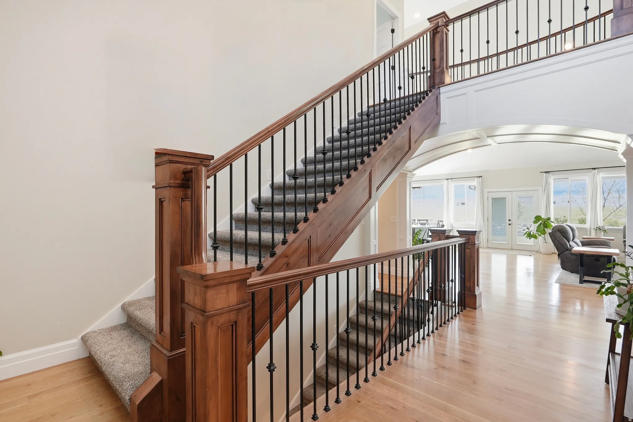 Staircase with french doors, wood finished floors, and a high ceiling