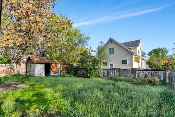 Rear view of house with a fenced backyard and a storage shed.