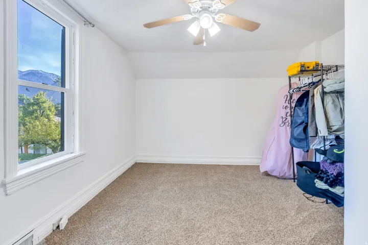 Lofted ceiling, light carpet, ceiling fan, and a mountain view.