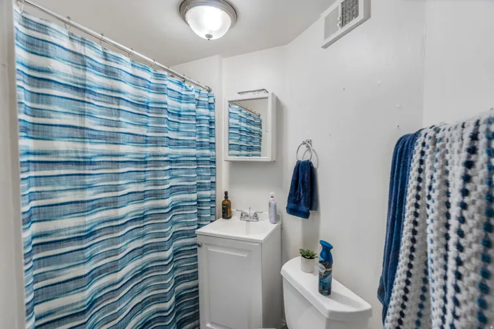 Full bath with vanity and curtained shower.