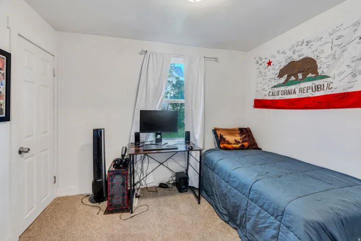 Carpeted bedroom featuring a desk and baseboards.