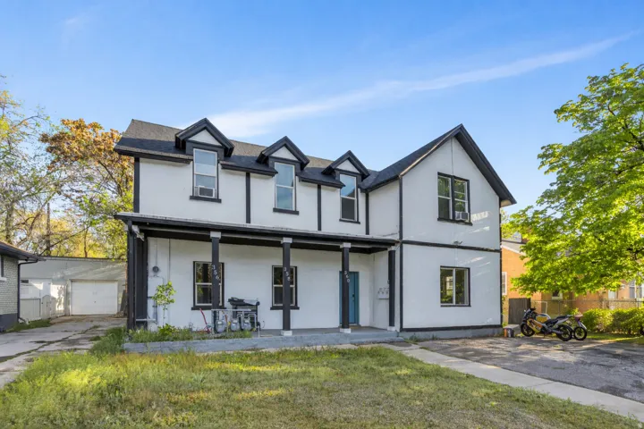 View of front of house featuring a porch, an outbuilding, stucco siding, and a detached garage