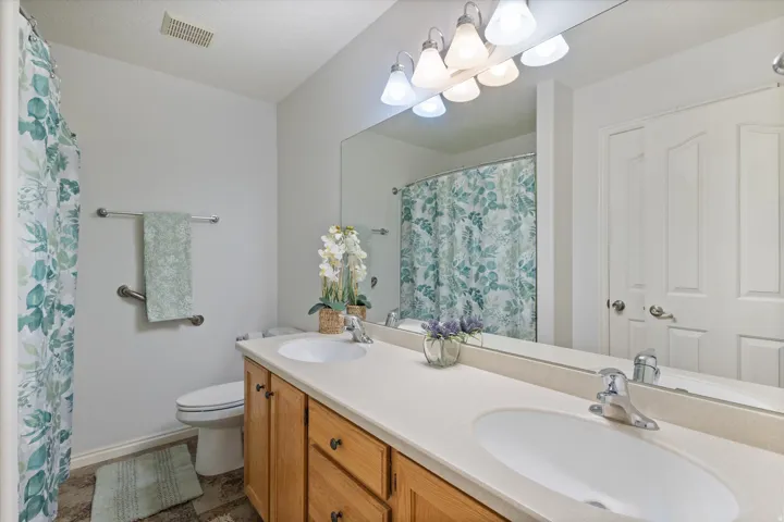 Full bath with double vanity and a shower with shower curtain
