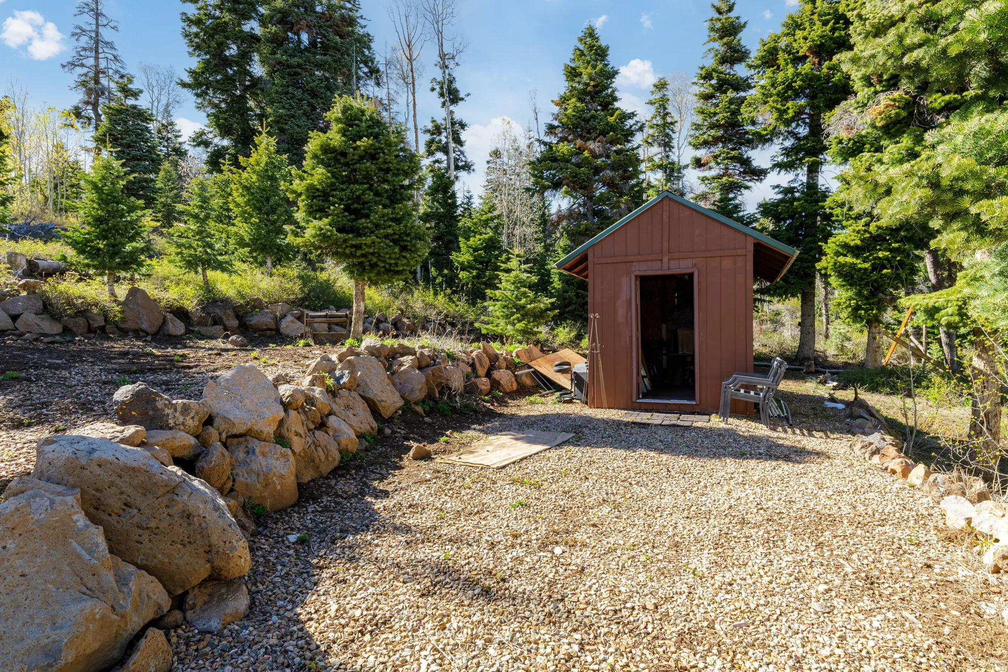 Rock Landscaping & Outbuilding: Custom rock retaining walls frame the path to the versatile storage shed.