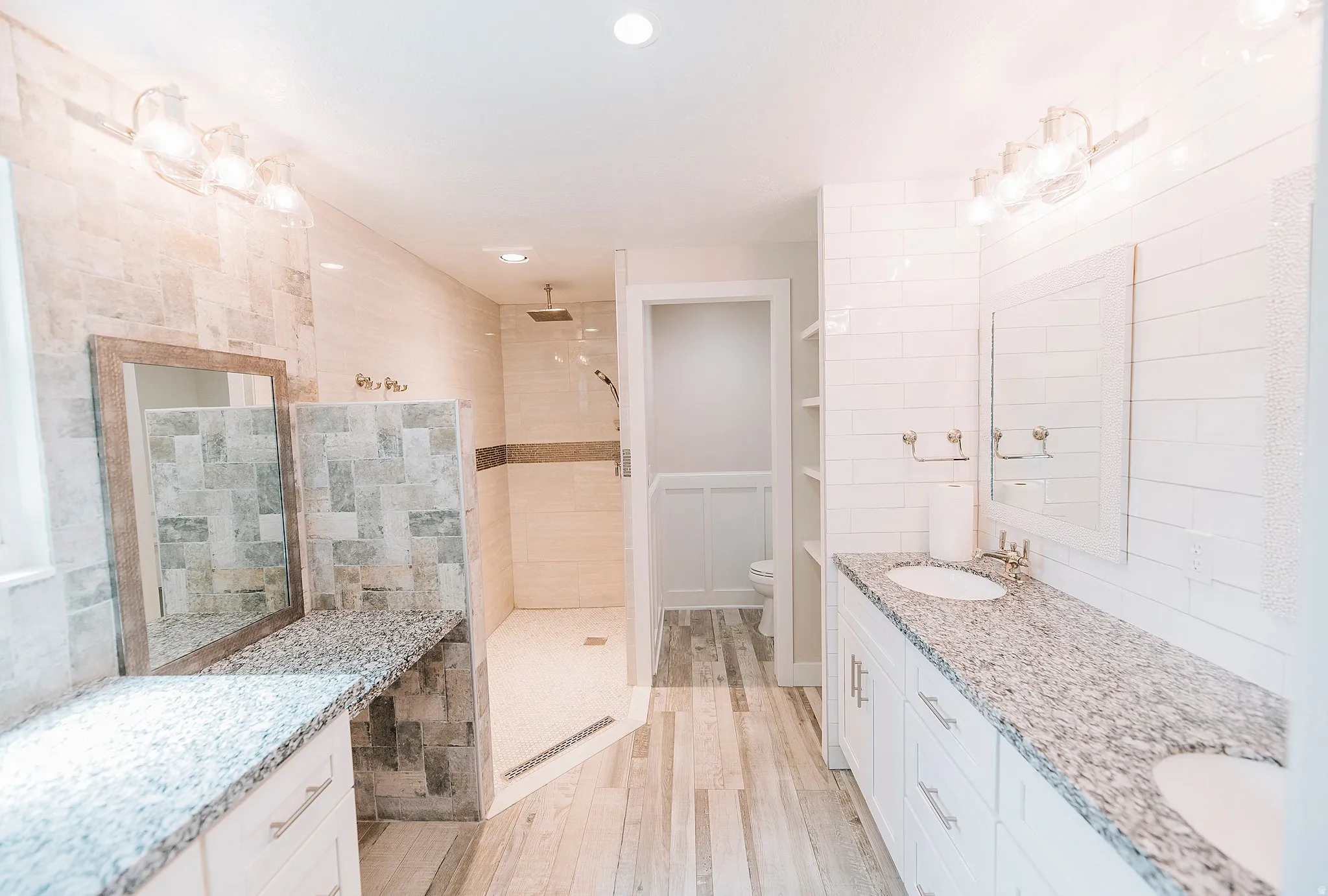Bathroom with double vanity, a walk in shower, and light wood-style flooring