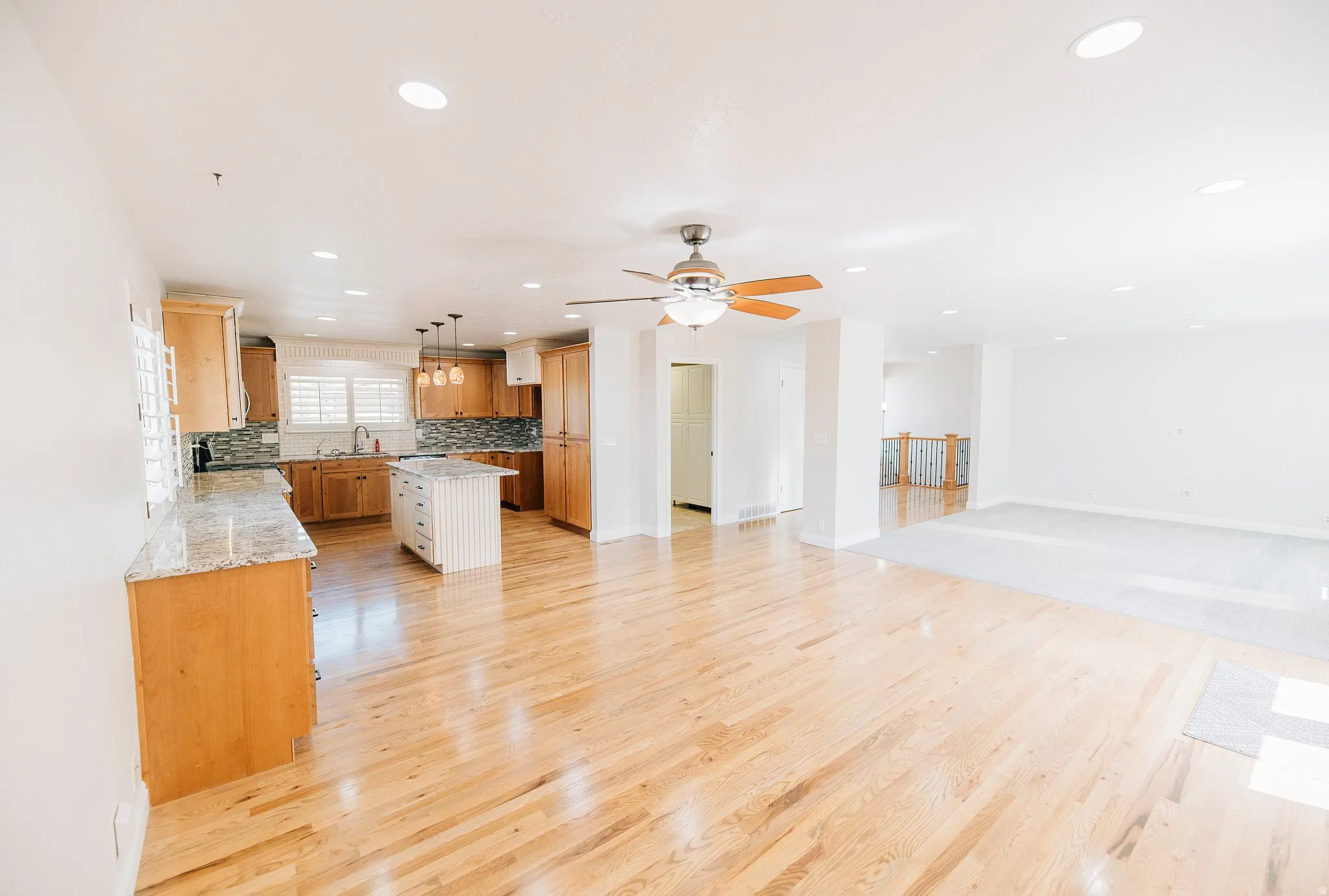 Kitchen featuring a center island, open floor plan, hanging light fixtures, light wood-style flooring, and light stone counters