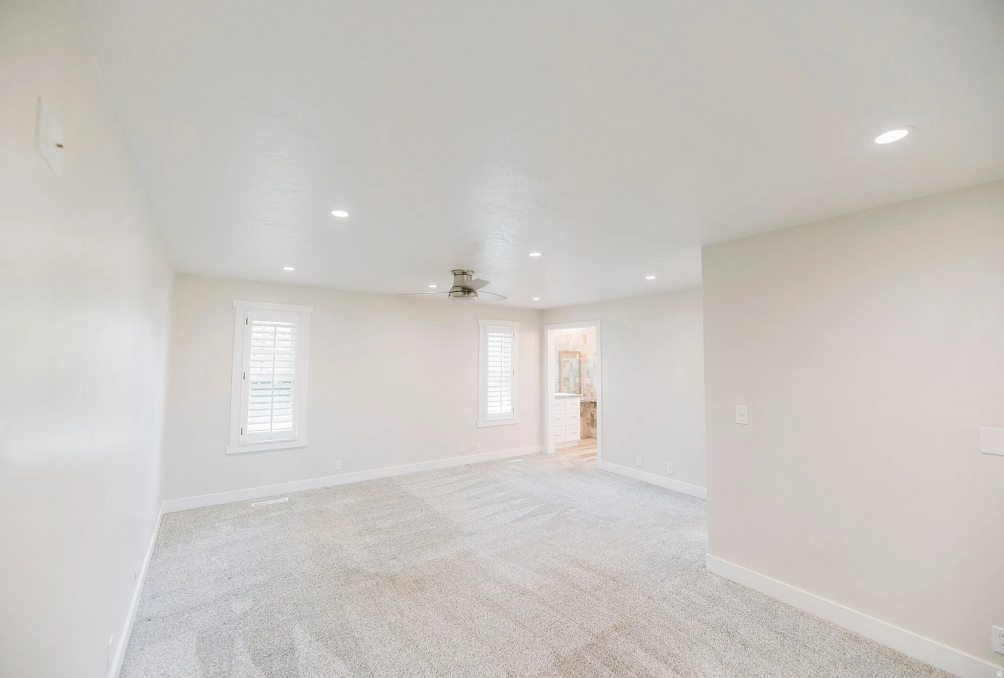 Empty room featuring light colored carpet, recessed lighting, and a ceiling fan