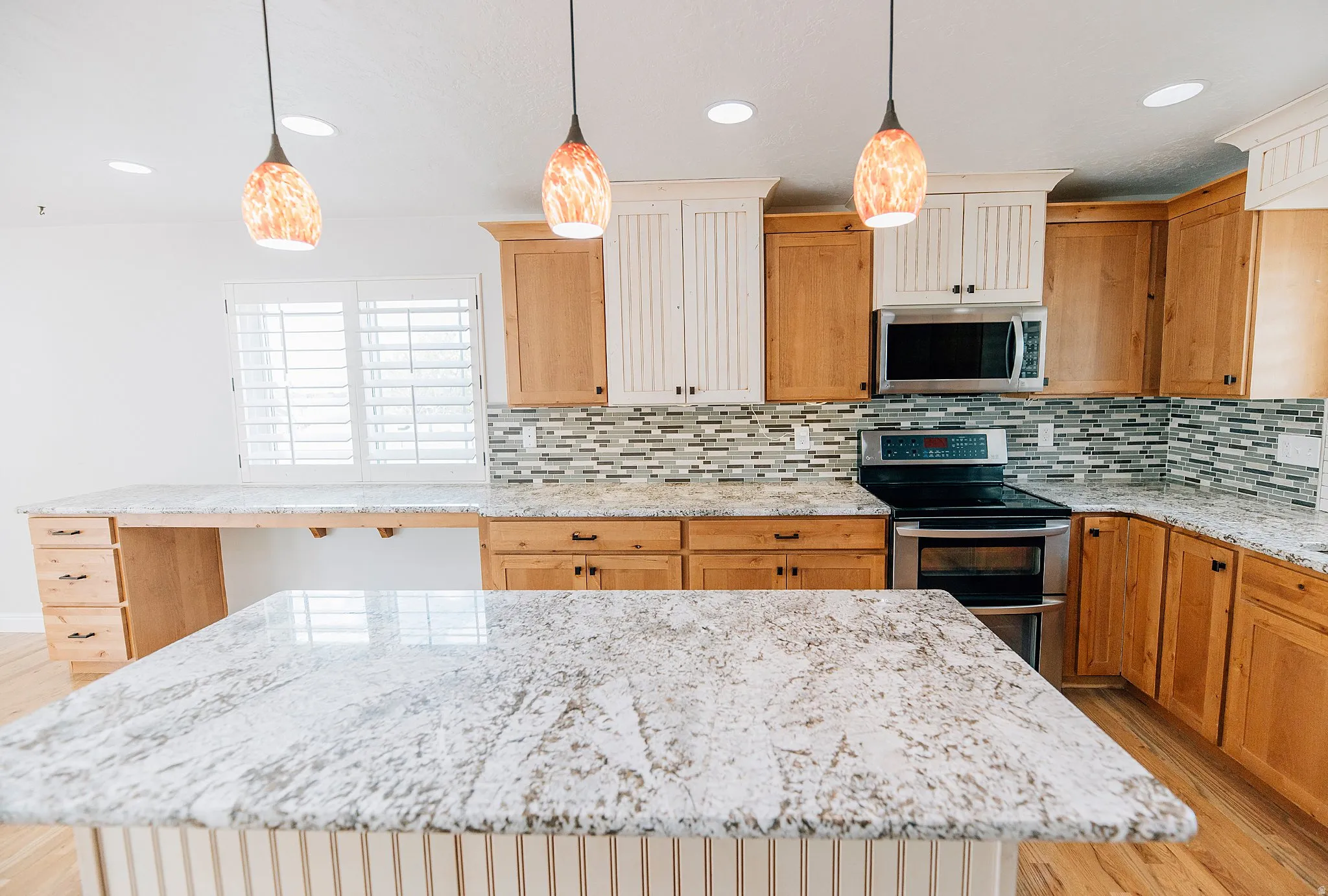 Kitchen featuring light wood-type flooring, stainless steel appliances, and light stone counters