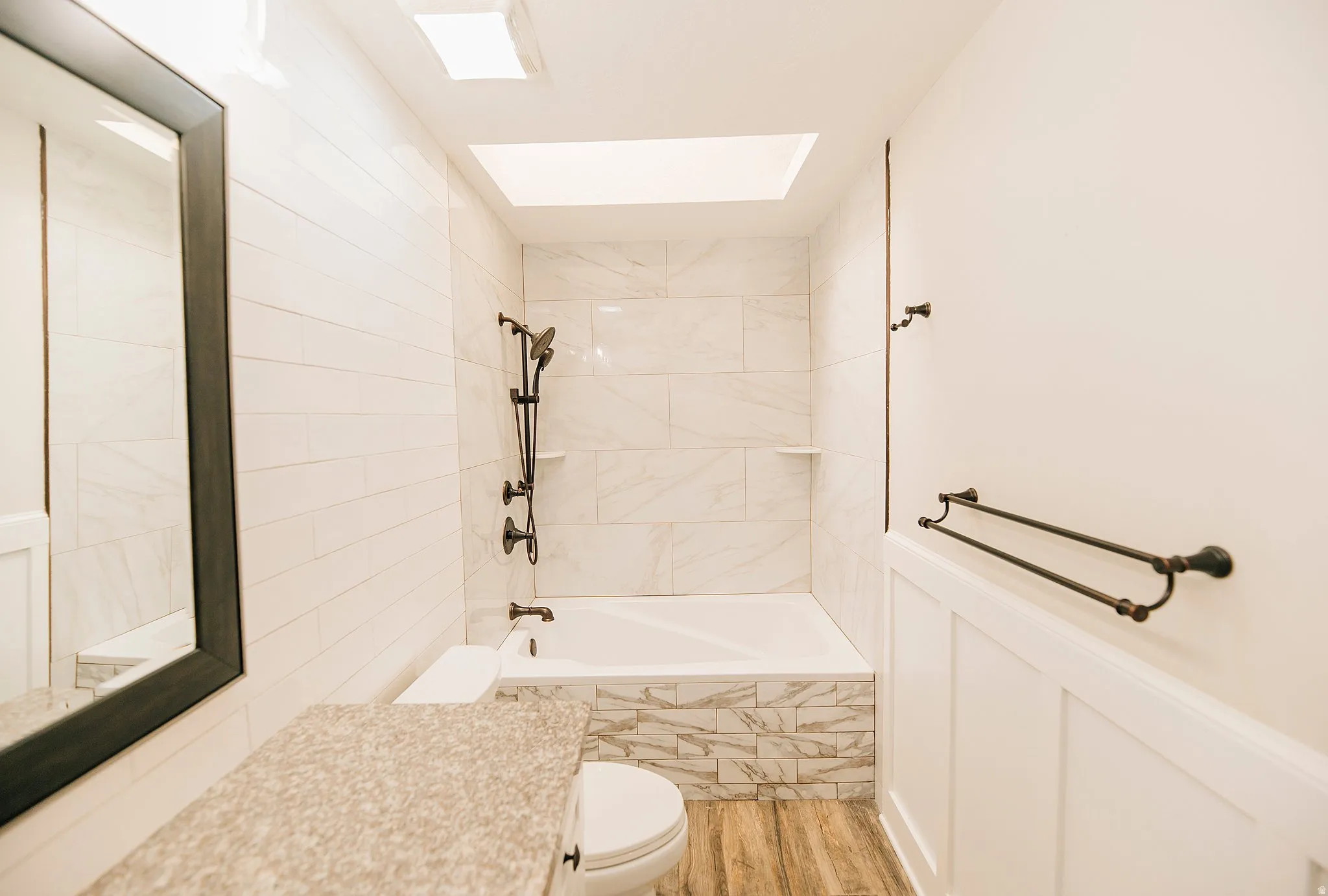 Bathroom with light wood finished floors, vanity, and tiled shower / bath combo
