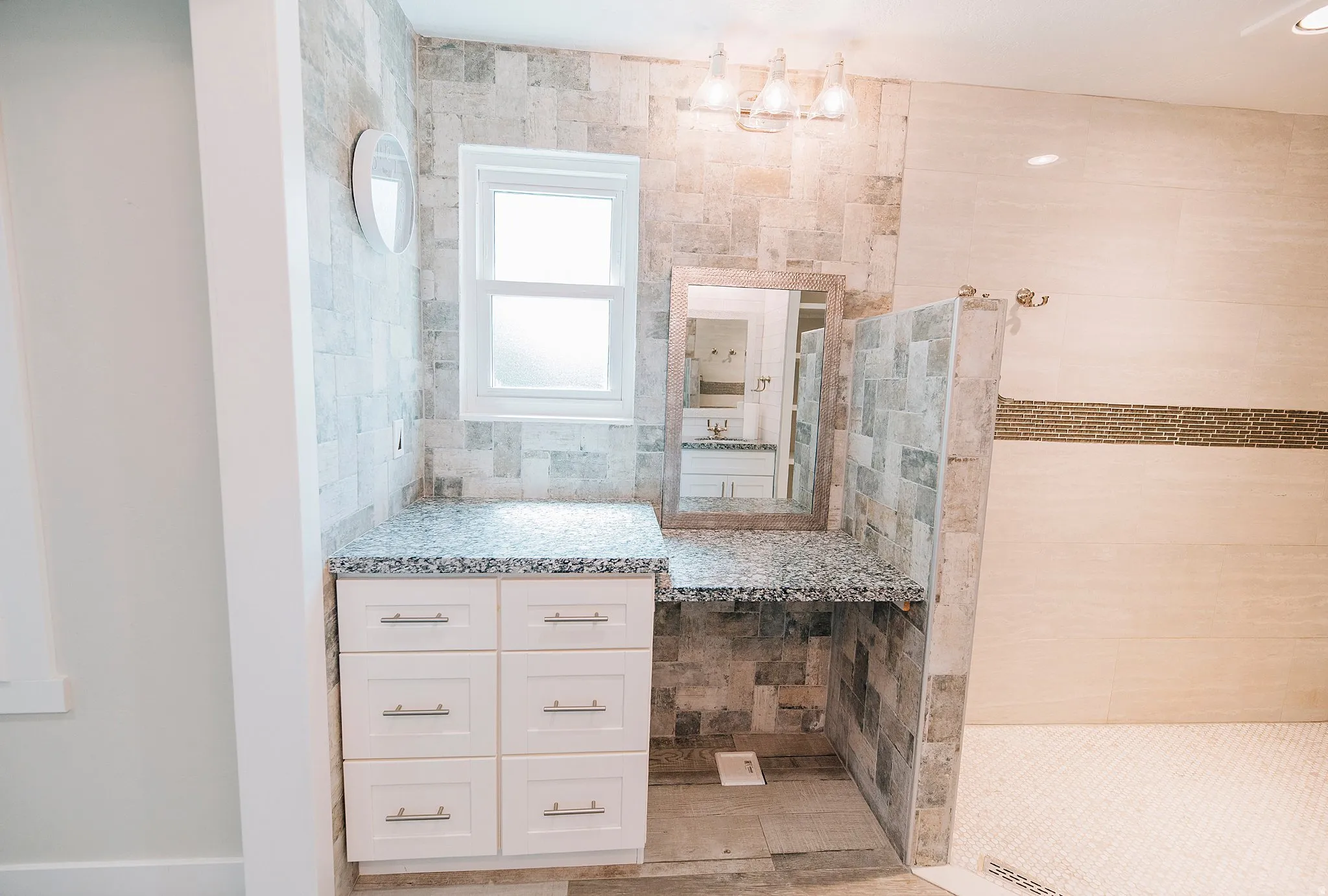 Bathroom featuring vanity, a walk in shower, and tile walls