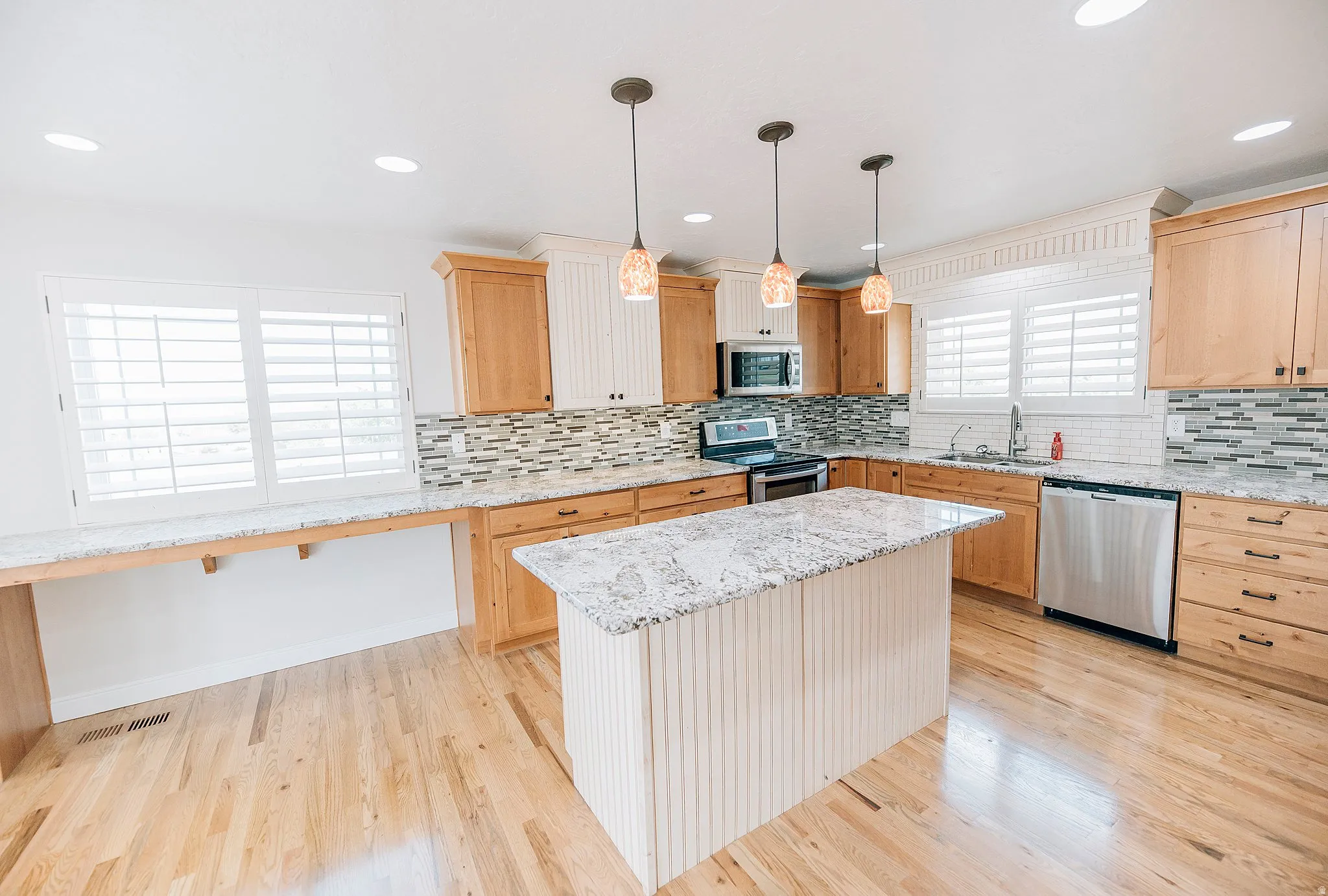 Kitchen with light wood finish cabinets, a center island, and light wood-style flooring