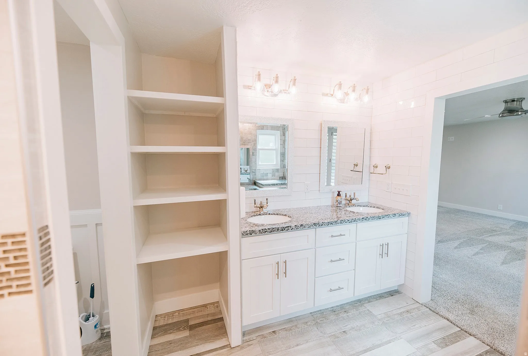 Full bath featuring double vanity, light colored carpet, a closet, and tile walls