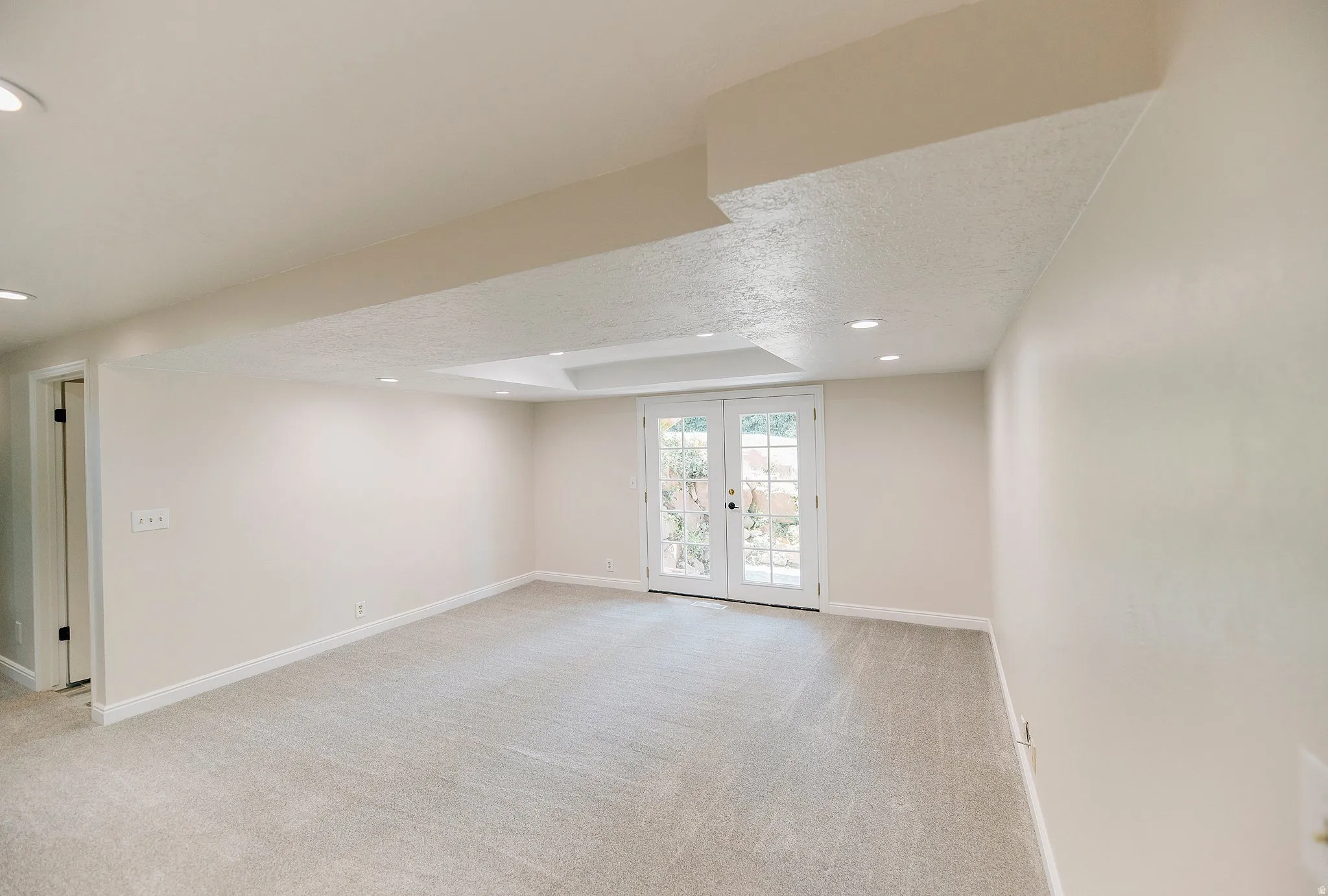 Spare room with light carpet, recessed lighting, french doors, and a textured ceiling