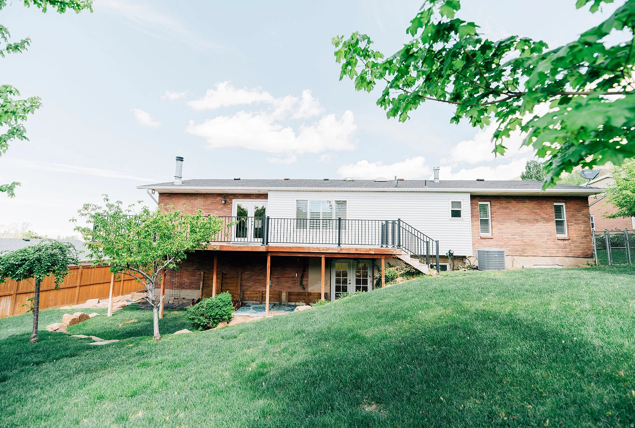 Rear view of property featuring brick siding and a deck