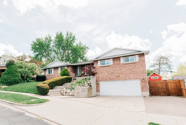 View of front facade featuring a gate, driveway, brick siding, and an attached garage