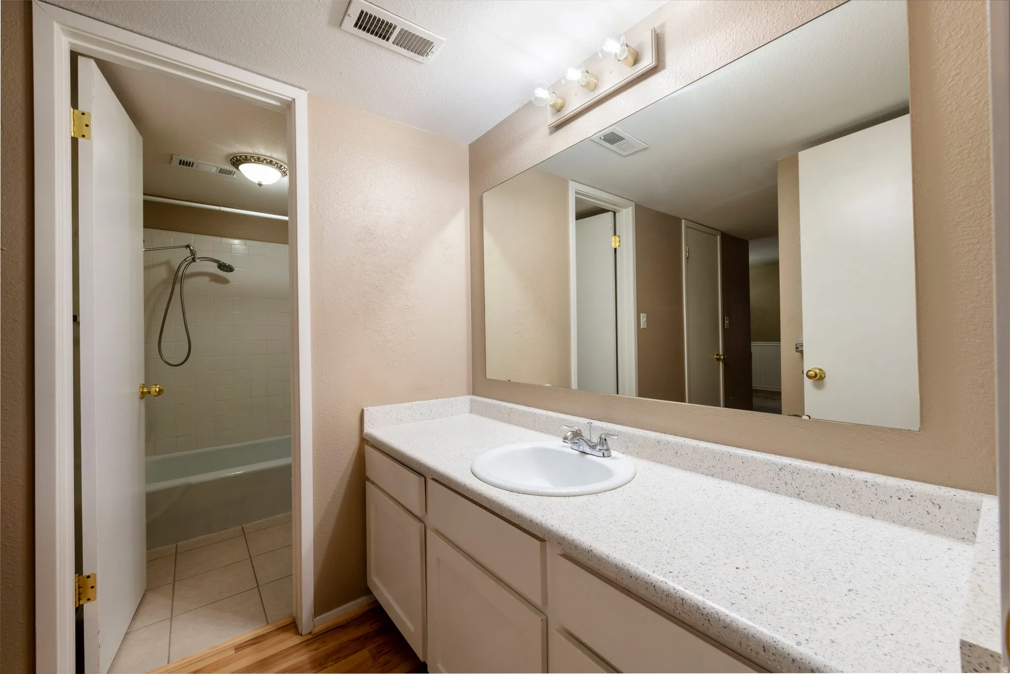Bathroom with vanity, washtub / shower combination, and light tile patterned flooring