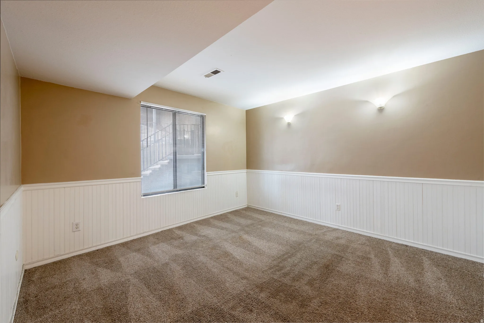 Carpeted spare room with wainscoting