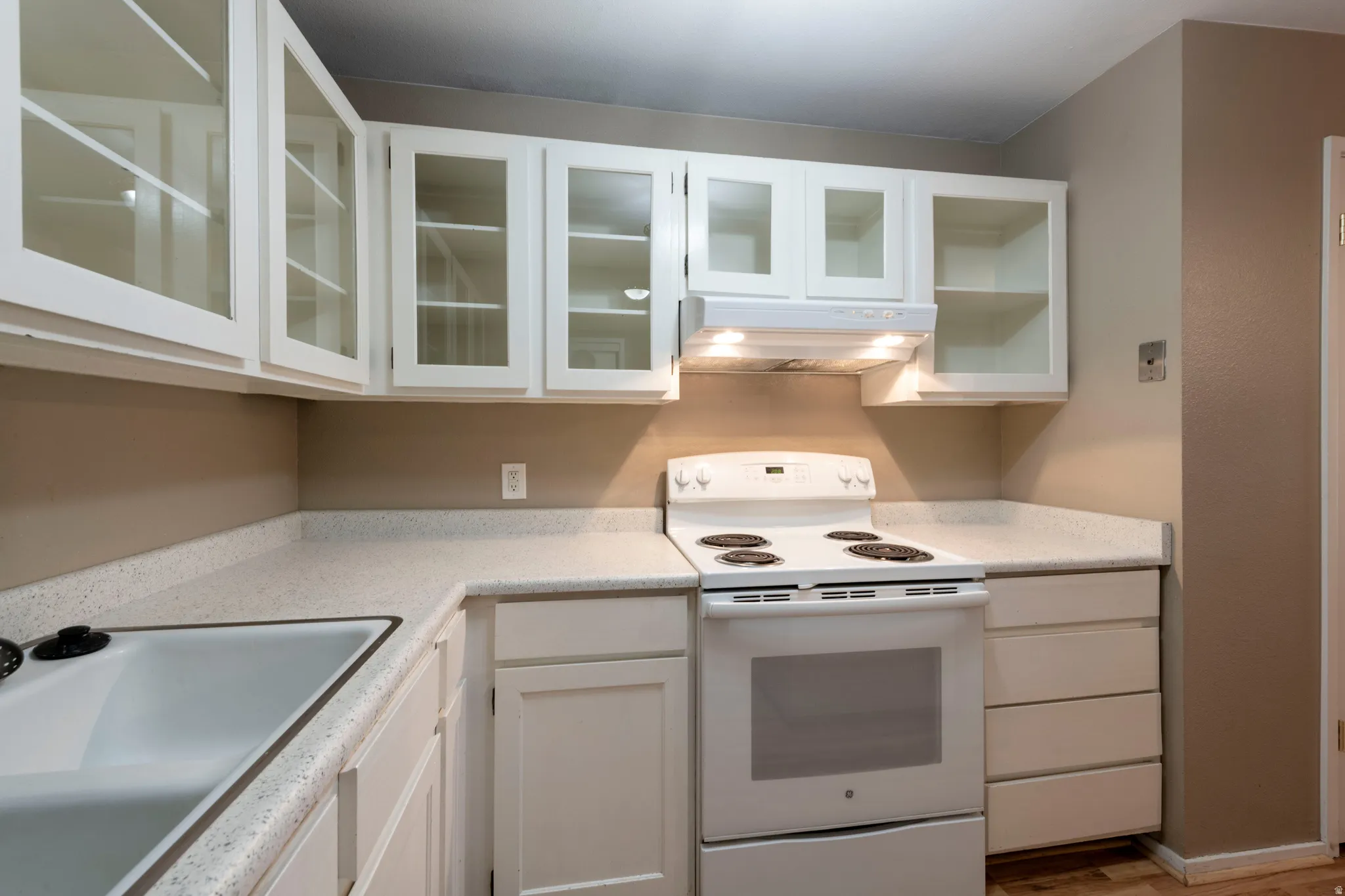 Kitchen featuring white electric stove, white cabinetry, light countertops, glass fronted cabinets, and wood finished floors