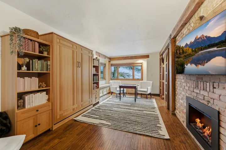 Office space with a brick fireplace and dark wood-type flooring