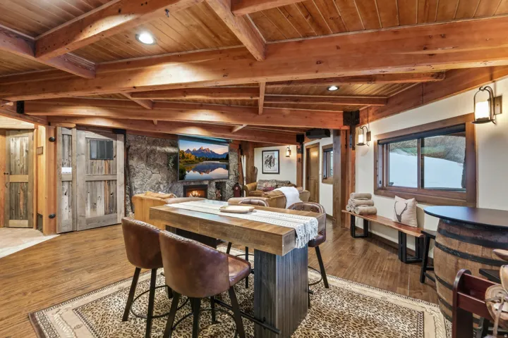 Dining room with a wood ceiling with exposed beams, a stone fireplace, wood finished floors, and recessed lighting