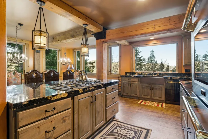 Kitchen with dark wood finished floors, pendant lighting, dark stone counters, dishwashing machine, and plenty of natural light