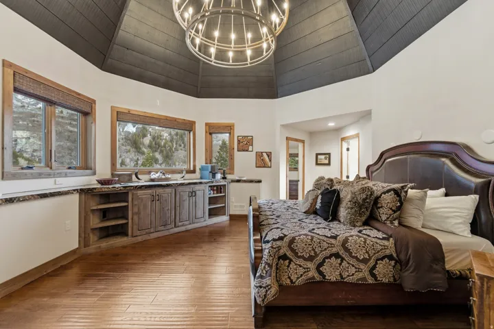 Bedroom featuring suspended lighting, dark wood finished floors, and vaulted ceiling