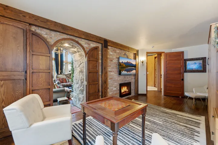 Living room with wood-type flooring, a brick fireplace, and arched walkways