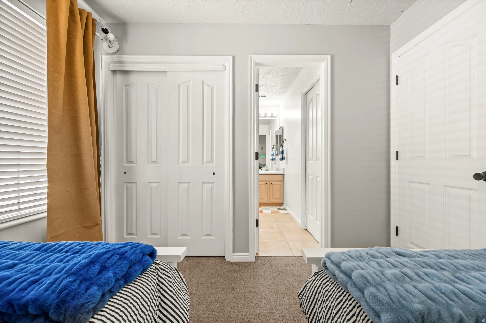 Bedroom with a textured ceiling, light colored carpet, and a closet