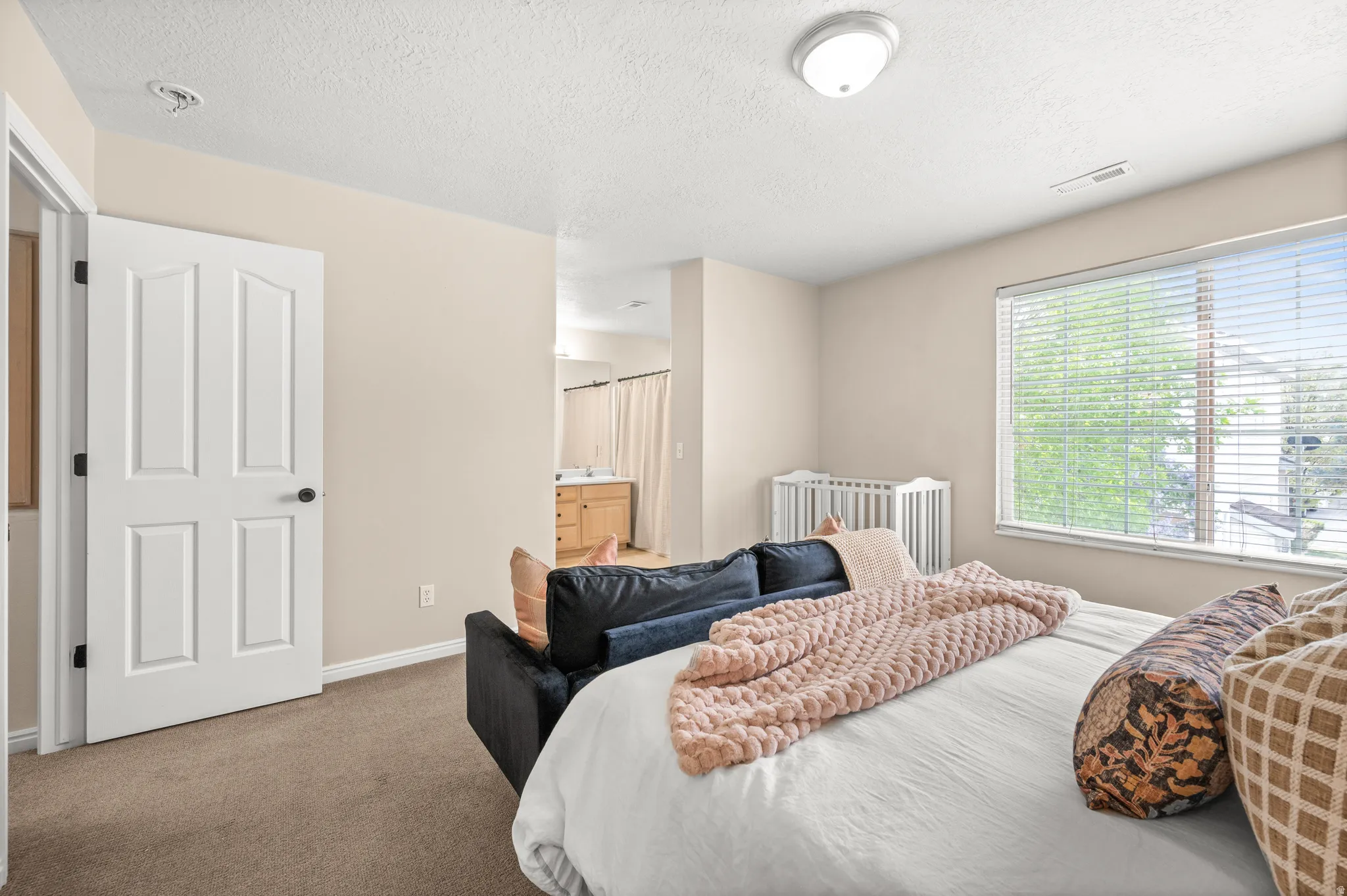 Carpeted bedroom featuring connected bathroom and a textured ceiling