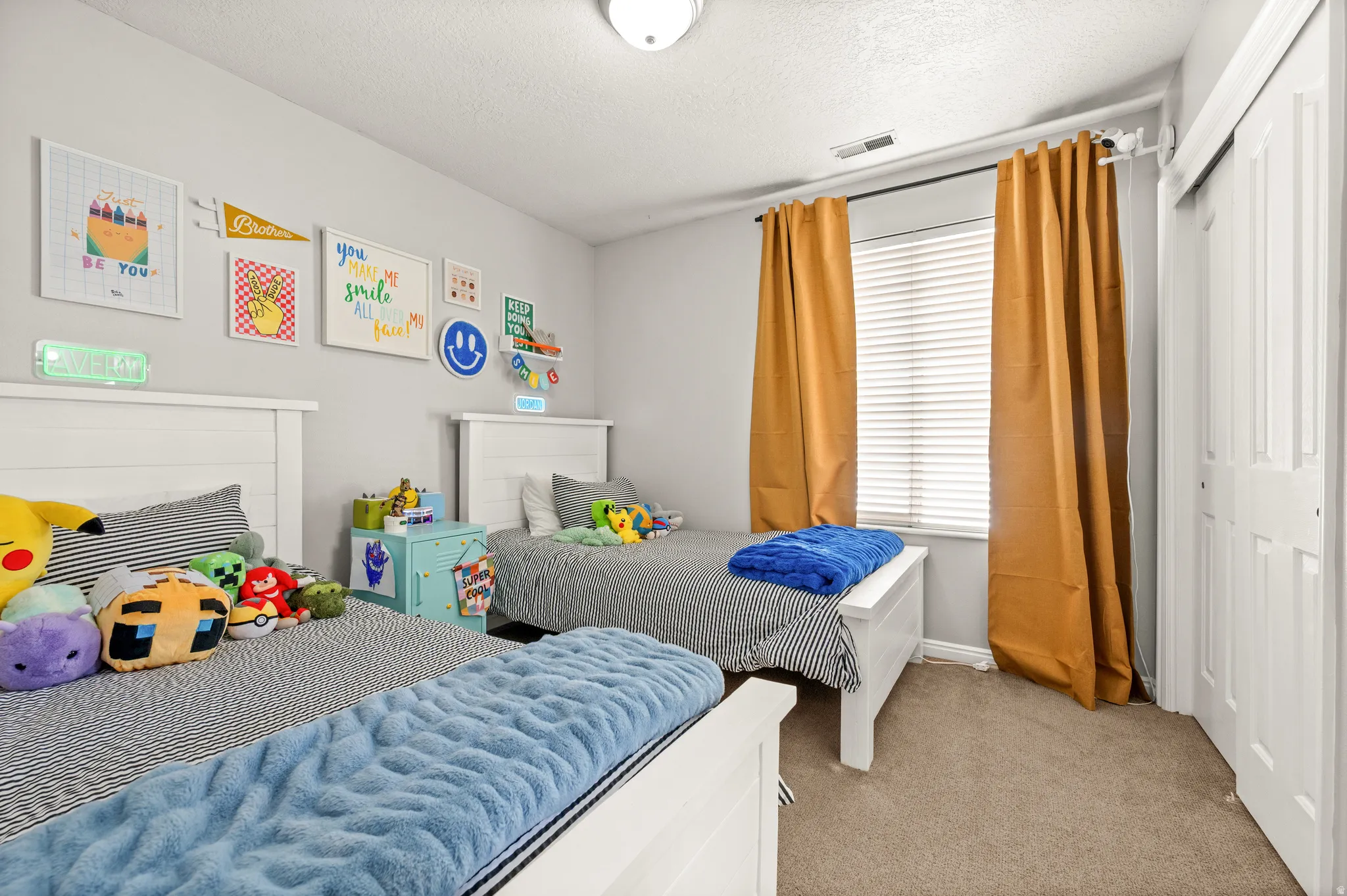 Bedroom with light colored carpet, a textured ceiling, and a closet