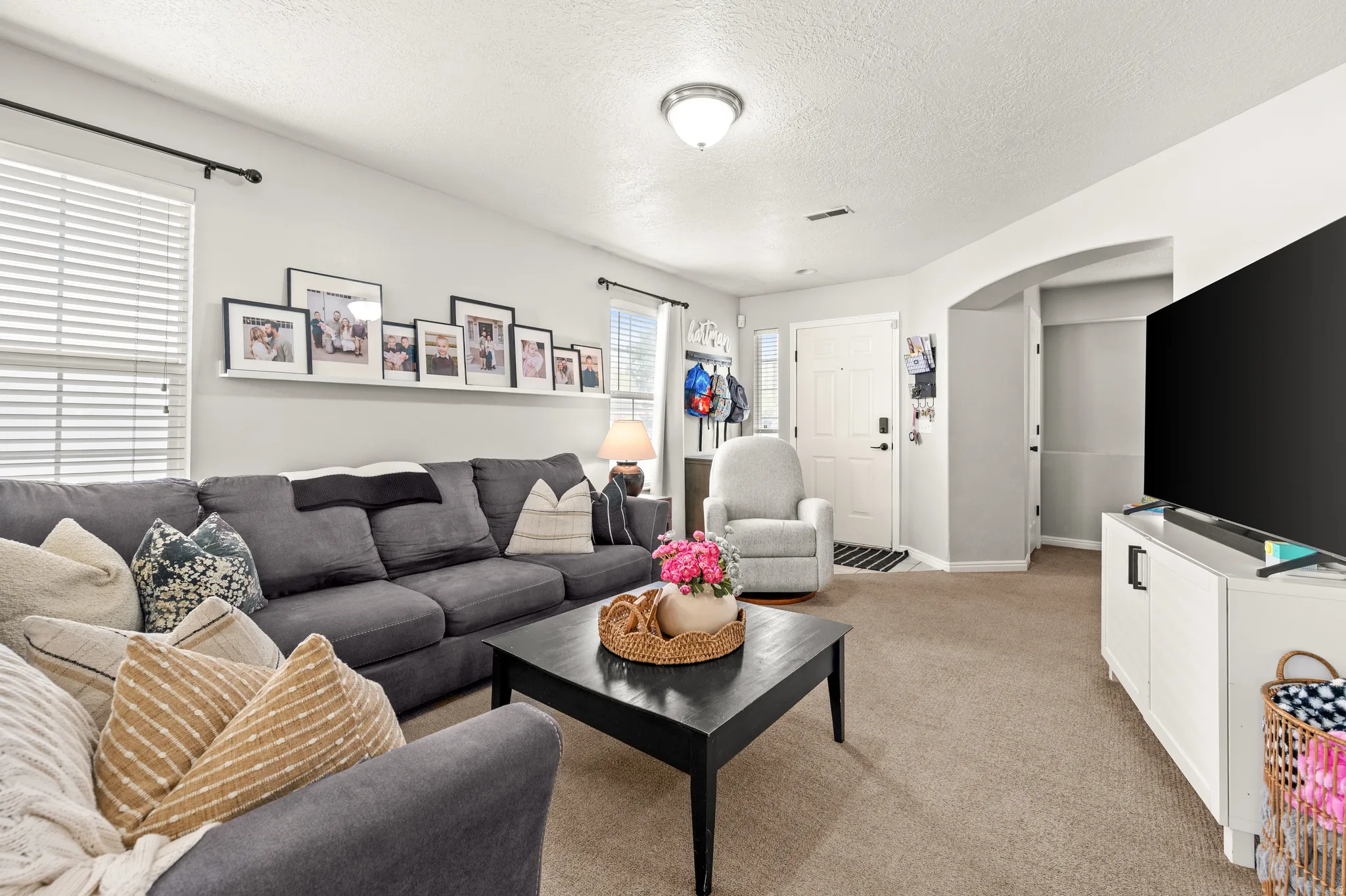 Living room featuring arched walkways, light carpet, and a textured ceiling
