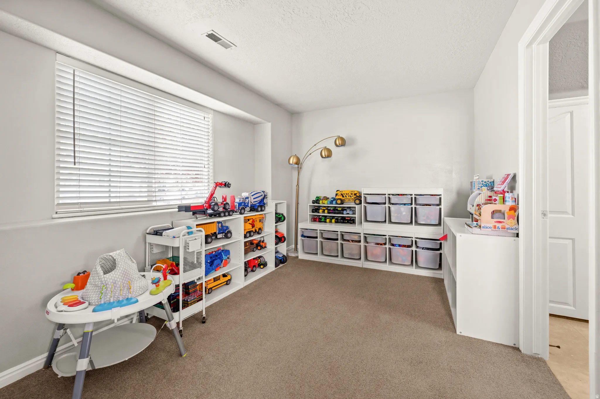 Rec room with light colored carpet and a textured ceiling