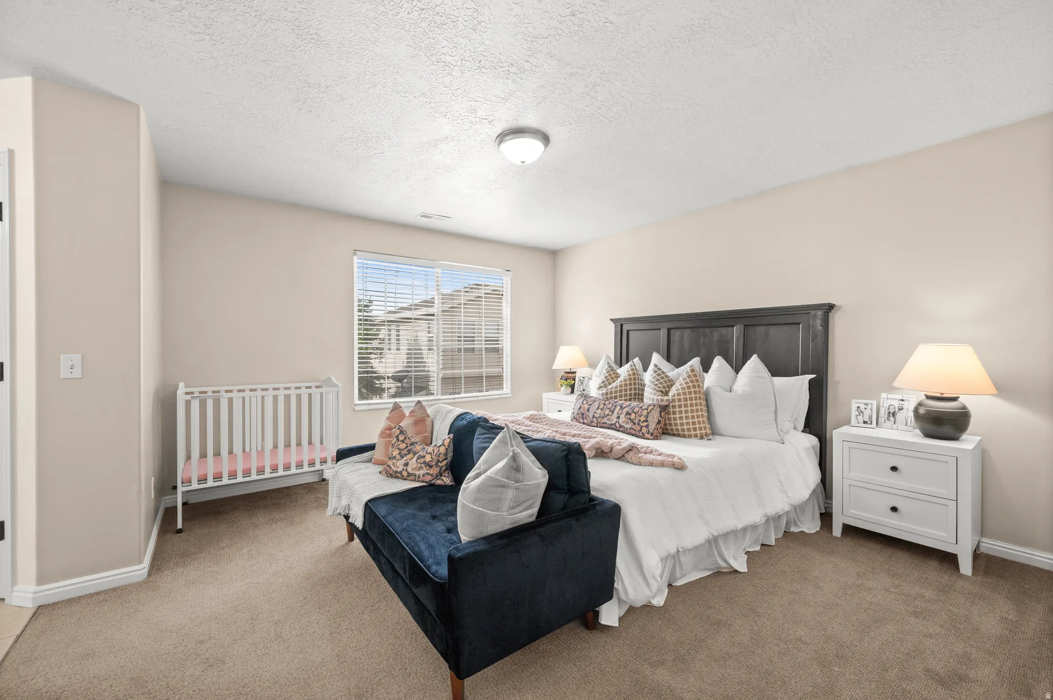 Carpeted bedroom featuring a textured ceiling and baseboards