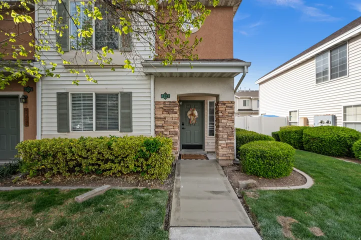 Entrance to property with stone siding, a lawn, and stucco siding